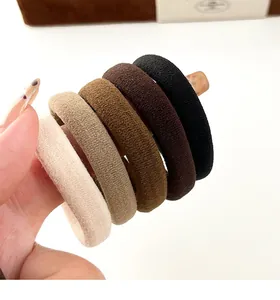 Gros plan de cinq élastiques à cheveux sans couture aux tons terreux en main