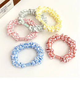 Detail of five plaid scrunchies in pastel colors with matching frosted cylinder beads