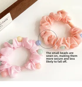 Détail de chouchous en tissu rose et orange avec perles colorées fixées fermement
