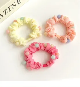 Détail de chouchous en mousseline colorée avec perles macaron en rose et jaune