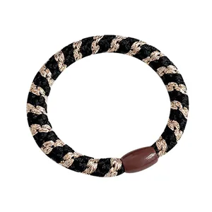 Élastique à cheveux tissé de fil doré avec joint en résine marron sur fond blanc