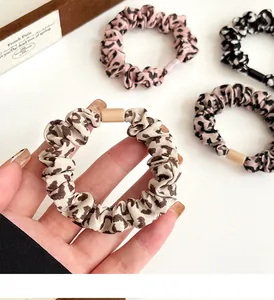 Detail von vier Leopardenmuster-Scrunchies in Beige, Rosa, Braun und schwarzem Chiffon