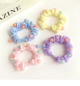 Détail de quatre chouchous perlés colorés en tissus bleu, jaune, rose et violet pastel