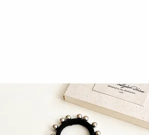 Détail d'un élastique à cheveux noir avec dix perles métalliques argentées lisses