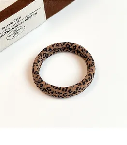 Detail view of brown leopard print hair tie made of soft elastic fabric on a white desk