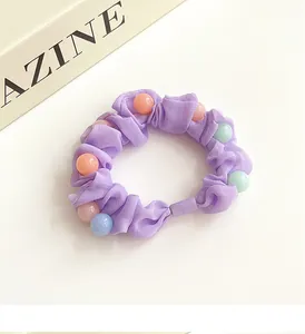 Détail du chouchou en mousseline violette avec perles décoratives pastel et texture élastique