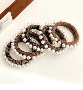 Detail showing leopard print hair ties with embedded white pearls and elastic fabric texture