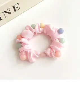 Gros plan détaillé du chouchou en tissu rose avec perles macaron sur fond blanc