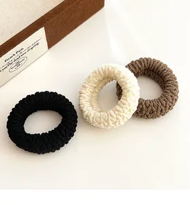 Detailed view of three knitted hair ties in black, beige, and coffee brown textures