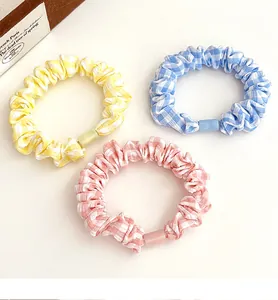 Detailed view of three plaid hair scrunchies in yellow, blue and pink cotton fabric