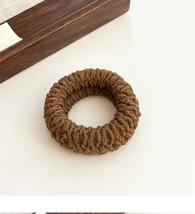 Macro detail of the caramel knit texture and ribbed pattern on the elastic hair tie