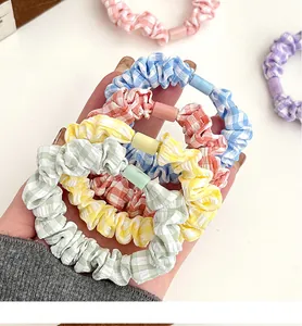 Close-up of pastel plaid elastic scrunchies in various colors held in hand