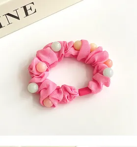 Détail d'un chouchou rose avec perles décoratives et tissu en mousseline plissée