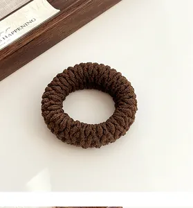 Macro detail of coffee brown thick braided hair tie showing spiral woven texture