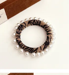 Detailed view of leopard print fabric scrunchie with elegant faux pearl embellishments
