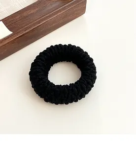Detail of a thick black elastic hair tie with textured knit for high-strength ponytails