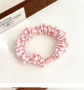 Detailed shot of pink gingham plaid scrunchie with soft fabric texture and plastic clasp