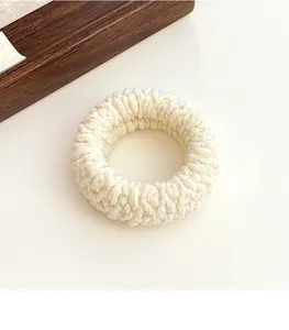 Macro detail of creamy white knitted scrunchie showing soft textured wool yarn