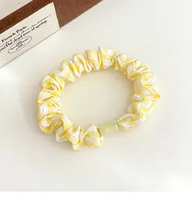 Detail of yellow gingham hair scrunchie with a translucent light green acrylic bead