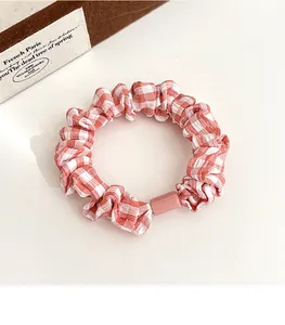 Close-up of pink and white checkered scrunchie with a small decorative plastic buckle