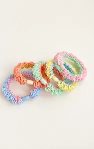 Close-up of five macaron-colored ruffled hair scrunchies with matching plastic connectors