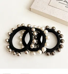 Détail de trois chouchous noirs élastiques avec perles fantaisie et perles en métal