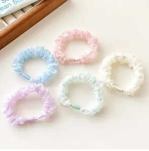 Detailed view of five pastel shimmering organza scrunchies in assorted soft colors