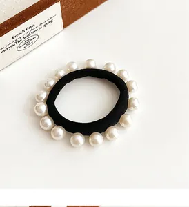 Détail d'un élastique à cheveux noir haute élasticité orné de perles blanches sur fond clair