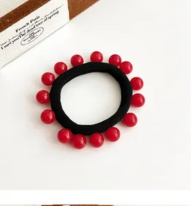 Détail d'un élastique à cheveux noir avec perles rouges brillantes et texture souple