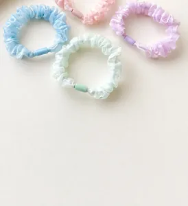 Detail of four pearlescent scrunchies in pastel blue, pink, purple and mint green colors