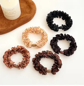 Detailed macro view of five high-elasticity ruffled hair ties in elegant earth tones