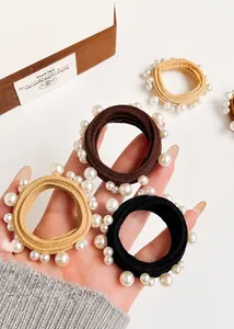 Close-up of pearl elastic hair ties in brown, black, and beige colors on a white surface