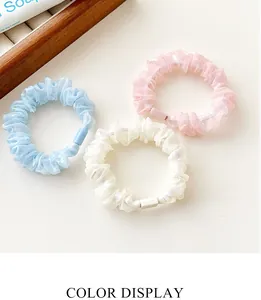 Close-up of three pearlescent mesh hair scrunchies in blue, pink, and white pastel colors