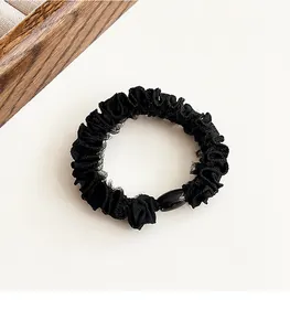 Detalle de un coletero negro plisado con una cuenta ovalada elegante sobre fondo claro