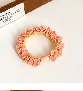 Detail of pink and yellow bicolored scrunchie with scalloped edges and orange buckle