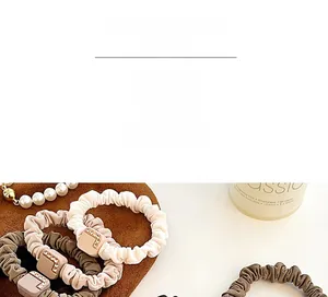 Detail of elegant pleated hair scrunchies with square rhinestone buckles in neutral tones