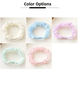 Detail showing five pastel silk scrunchies in cream, blue, purple, green, and pink colors