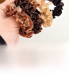 Detailed view of coffee-toned ruffled scrunchies with elastic glossy silk texture