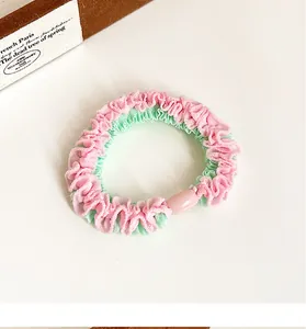 Detail of pink and green pleated scrunchie with a matching pink oval bead accessory