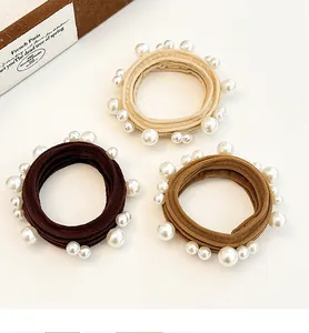 Detailed view of beige and brown elastic hair ties with elegant pearl embellishments
