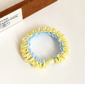 Detail of blue and yellow ruffled scrunchie with acrylic bead on a soft background