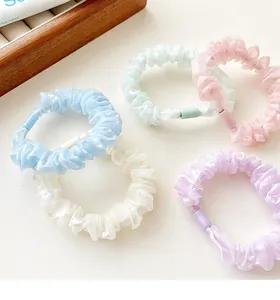 Detailed view of five pastel floral organza scrunchies in blue, white, green, pink and purple