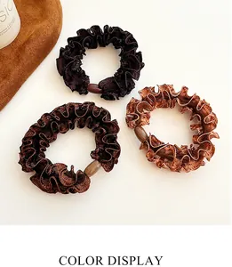Detailed macro view of three textured ruffled hair scrunchies with decorative oval beads