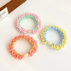 Three colorful wavy hair ties in pink, yellow, and orange on a clean white background