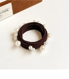 Close-up of brown elastic hair tie featuring white pearls on high-stretch nylon cord