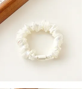 Detail of cream white mesh scrunchie featuring shiny floral prints and pleated fabric