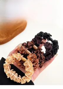 Lace ruffle hair scrunchies with beads in champagne and brown tones shown in hand