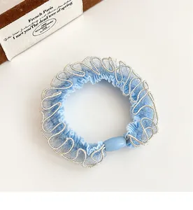 Dettaglio dello scrunchie in pizzo azzurro con bordo argentato e perla ovale