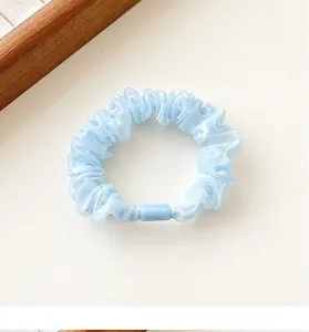 Detail of light blue pleated organza scrunchie with plastic clasp on white background