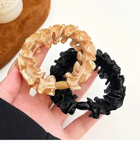 Close-up of champagne gold and black pleated lace hair scrunchies with oval beads